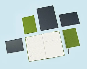 Different versions of the weekly planner in green and gray linen arranged around an open copy