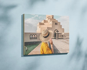 Photo of a woman with a straw hat in front of architecture mounted on wood