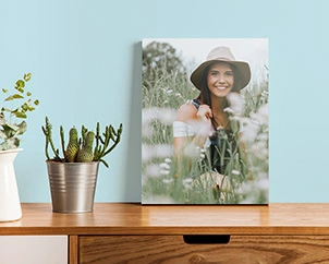 Photo of woman with hat standing on dresser in field of flowers