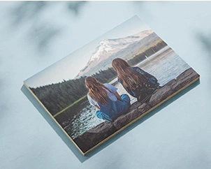 Photo of two women from behind looking at mountains mounted on wood